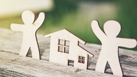 Kleine Holzmännchen neben einem kleinen Modellhaus