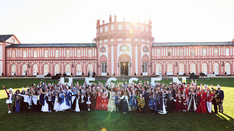 Boris Rhein steht mit den hessischen Tollitäten vorm Biebricher Schloss. Sie halten Buchstaben in die Höhe, die das Wort "Hessen" ergeben. 