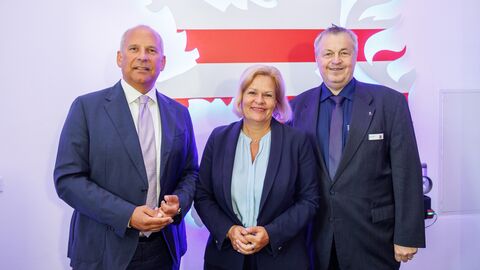 Innenminister Poseck steht gemeinsam mit Bundesinnenministerin Faeser und Rolf Richter vor einer Wand zum Gruppenfoto aufgestellt.