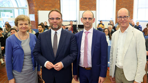 Eine Frau und vier Männer stehen nebeneinander und blicken in die Kamera