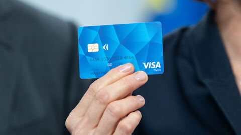 Eine Hand hält eine blaue Geldkarte hoch.