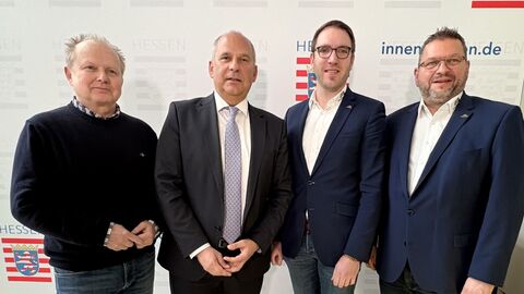 Vier Männer stehen nebeneinander - hinter ihnen ein Aufsteller mit der Aufschrift "Hessisches Ministerium des Innern, für Sicherheit und Heimatschutz"